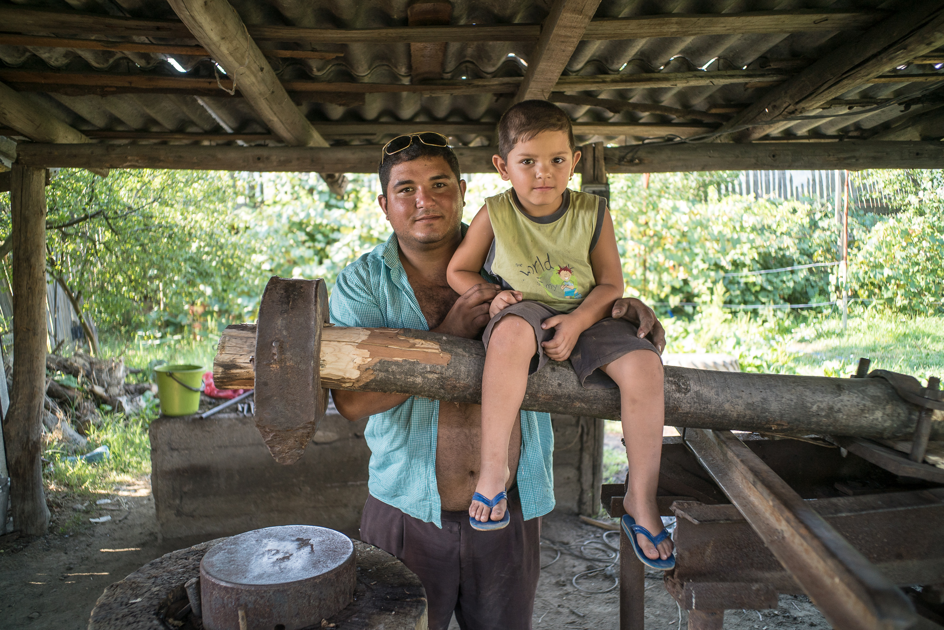 Geo împreună cu fiul său, Ionuț, în atelierul de căldărărie al tatălui său, Ilie, în Corcova, România, august 2015. Atelierul este astăzi năpădit de buruieni și acoperit de rugină; Ilie și Geo locuiesc în Belgia și nu mai practică meseria tradițională de ani buni. Geo împreună cu fiul său, Ionuț, în atelierul de căldărărie al tatălui său, Ilie, în Corcova, România, august 2015. Atelierul este astăzi năpădit de buruieni și acoperit de rugină; Ilie și Geo locuiesc în Belgia și nu mai practică meseria tradițională de ani buni.