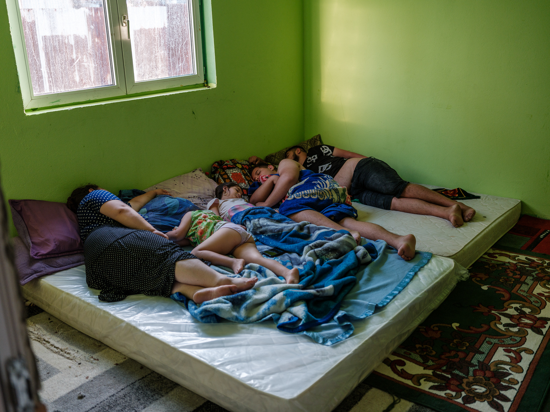 Marina doarme împreună cu copiii și cu verișorul ei, iar Geo direct pe jos, unde e mai răcoare. Dormitorul lor nu este încă gata. Corcova, România, august 2025 Marina doarme împreună cu copiii și cu verișorul ei, iar Geo direct pe jos, unde e mai răcoare. Dormitorul lor nu este încă gata. Corcova, România, august 2025