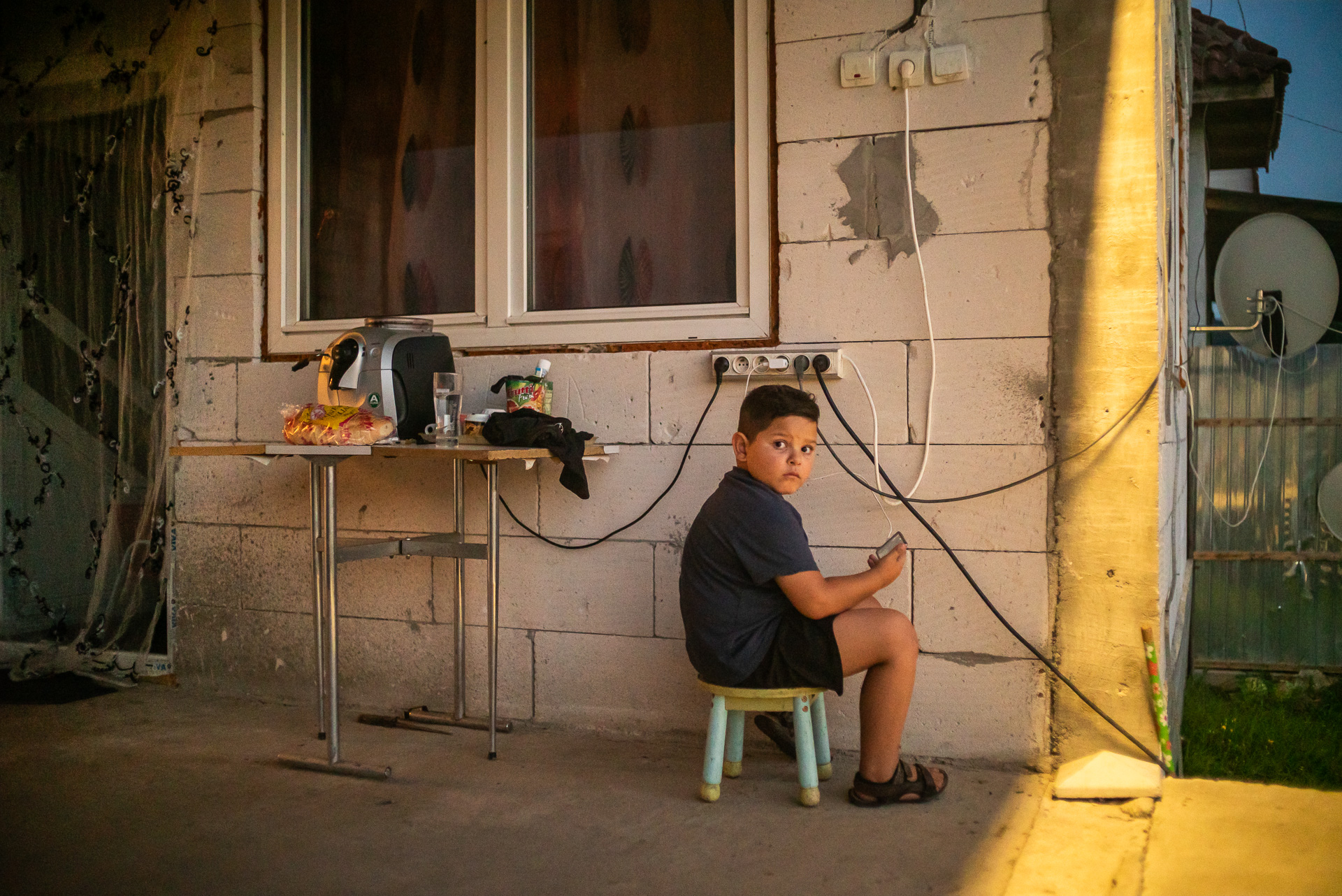 Ionuț se joacă la telefon pe prispa casei din Corcova, România, iulie 2017 Ionuț se joacă la telefon pe prispa casei din Corcova, România, iulie 2017