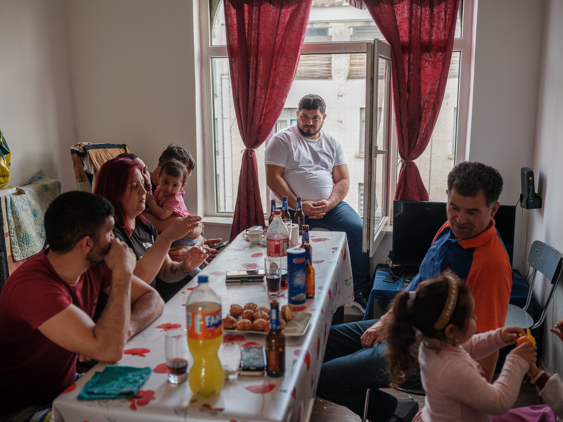 Geo acasă la fratele lui, Țucă, în cartierul Schaerbeek din Bruxelles. De la stânga la dreapta: Țucă, nașa lui, Elena, și nașul Dominic care o ține pe Estera, fiica lui Țucă în brațe, unchiul Costică, care tocmai a venit din România, Geo, tatăl lui, Ilie, și Andreea, fiica lui Geo. Belgia, iunie 2024 Geo acasă la fratele lui, Țucă, în cartierul Schaerbeek din Bruxelles. De la stânga la dreapta: Țucă, nașa lui, Elena, și nașul Dominic care o ține pe Estera, fiica lui Țucă în brațe, unchiul Costică, care tocmai a venit din România, Geo, tatăl lui, Ilie, și Andreea, fiica lui Geo. Belgia, iunie 2024