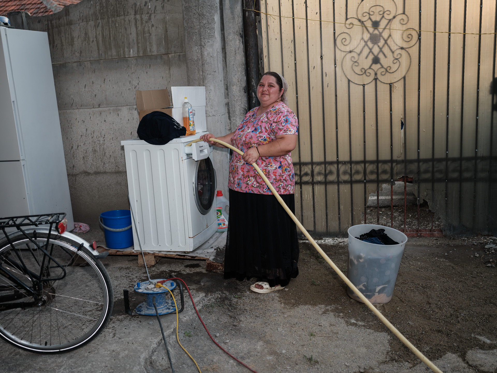 Marina umple mașina de spălat cu furtunul pentru că satul Corcova nu are apă curentă. România, august 2025 Marina umple mașina de spălat cu furtunul pentru că satul Corcova nu are apă curentă. România, august 2025